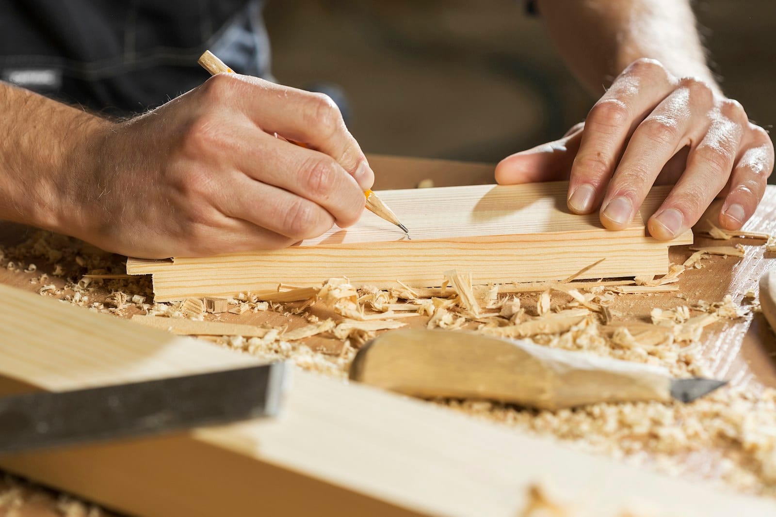 Carpenter marking a timber board with a pencil